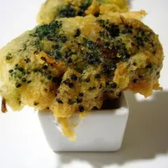Brocoli en tempura crujiente, servido en un pequeño cuenco blanco con salsa.