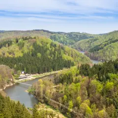Góry Sowie w zieleni, z rzeką i mostem. Wyobraź sobie, jak dzieci biegają po ścieżkach wśród drzew.