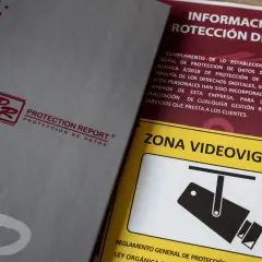 Documentos sobre protección de datos y un cartel de "Zona Videovigilada", parte de una feria de seguridad.