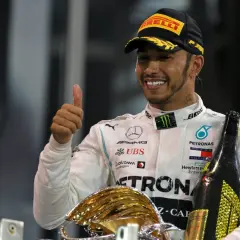 Lewis Hamilton, jeden z najlepsi kierowcy F1 wszechczasów, świętuje zwycięstwo z pucharem i szampanem.