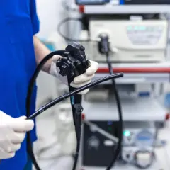 Lekarz w białych rękawiczkach trzyma endoskop. Przygotowania do gastroskopii w znieczuleniu ogólnym.