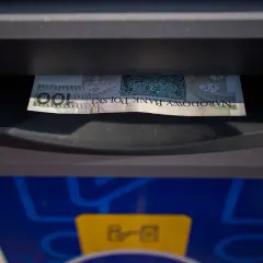 Sto złotych w banknocie wychodzi z bankomatu. To mój etatowy dochód, który właśnie wypłaciłem.