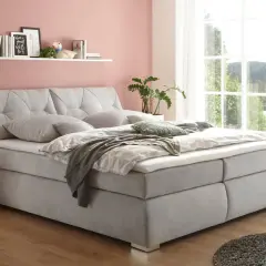 Einladendes, graues Boxspringbett mit gestepptem Kopfteil, das Ruhe und Harmonie ausstrahlt – perfekt für ein Feng Shui Bett.