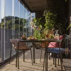 Jak zrobić balkon w bloku? Przytulny, przeszklony balkon ze stolikiem, krzesłami i mnóstwem zieleni. Idealne miejsce na poranną kawę.