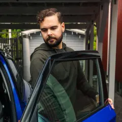 Man med skägg öppnar dörren till en blå bil. Kanske dags att tänka på att måste man serva bilen varje år för att den ska hålla sig i toppskick.