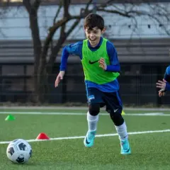 Zwei Jungen in Fußballtrikots trainieren auf einem Kunstrasenplatz. Sie sind voller Energie und Freude, während sie über das Feld rennen. Diese fussball spiele kinder sind ein toller Anblick!