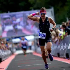 Kobieta w stroju sportowym biegnie, numer startowy 633. To jej trening na 10 km, a tłum kibicuje jej z boku.