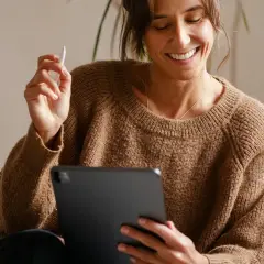 Uśmiechnięta kobieta z rysikiem w dłoni przegląda coś na tablecie. Jaki tablet, taki komfort pracy!