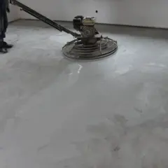 Pracownik poleruje betonową posadzkę maszyną. Powierzchnia jest gładka i lśniąca, tworząc nowoczesny wygląd.