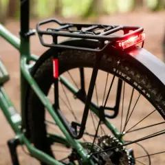 Zielony rower z zamontowanym bagażnikiem rowerowym i czerwoną lampką. Gotowy na wyprawę!