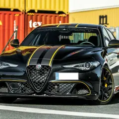 Czarna Alfa Romeo Quadrifoglio z żółtymi pasami i akcentami, gotowa do jazdy.