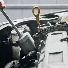 Mechanik sprawdza poziom oleju, co może być jednym z objawów uszkodzonej pompy oleju.