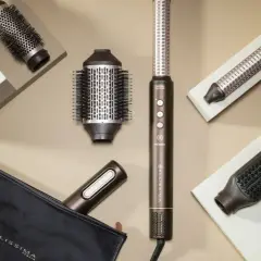 Herramientas para un blow out hair perfecto: cepillos redondos, un rizador y un cepillo plano, junto a un estuche.