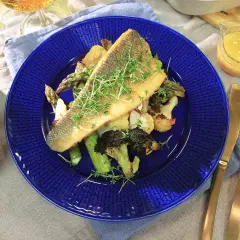 En läcker havsabborre med rostade grönsaker, perfekt för ett enkelt havsabborre recept. Serveras med en ljus sås och gyllene bestick.