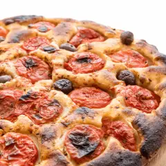Focaccia barese dorata e fragrante, con pomodorini succosi e olive nere, pronta per essere gustata.