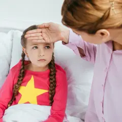 Mama sprawdza gorączkę córki, martwiąc się o objawy odwodnienia u dziecka.