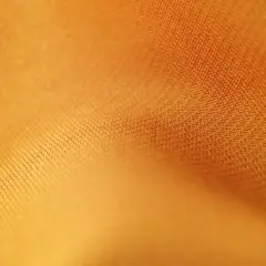 Texture d'un tissu orange vif, où chaque rayon fibre est visible, créant un motif subtil et doux.