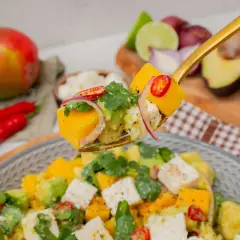 Ein Löffel voller Mango-Salat mit Avocado, Feta, roten Zwiebeln und Chili.