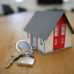 Une clé et un porte-clés en forme de maison, symbolisant le projet de vendre sa maison.