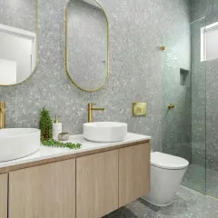 Modernos baños bonitos con lavabos sobre encimera, grifería dorada y azulejos de terrazo gris.