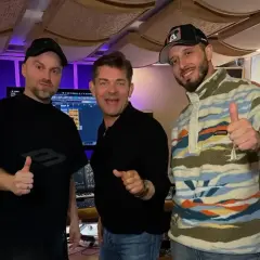 Mariusz Kalaga, jedna z gwiazd, w studiu nagraniowym z przyjaciółmi. Wszyscy pokazują kciuki w górę, gotowi do tworzenia muzyki.