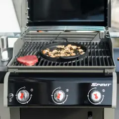 En portabel gasolgrill bäst i test förbereds med en rå biff och champinjoner. Kryddkvarn och saltkaret står redo.