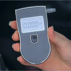 Dłoń trzyma alkomat z wyświetlaczem pokazującym 0.000.
