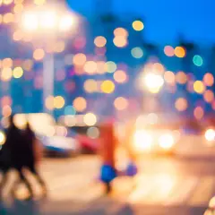 Rozmazane światła miasta nocą, jak widzi osoba z krótkowzrocznością. Rozmyte kształty ludzi i samochodów.