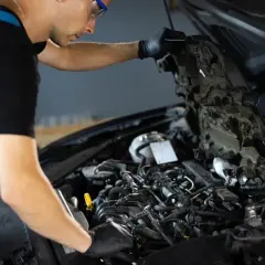 Mécanicien travaillant sur un moteur de voiture, vérifiant les composants pour éviter tout risque de colmatage.