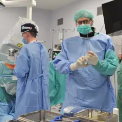 Chirurdzy w sterylnych strojach przygotowują się do skomplikowanej operacji kręgosłupa szyjnego. Czas jej trwania zależy od wielu czynników.