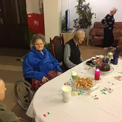 Wspólne świętowanie w domu seniora Zacisze. Przy stole tort, ciastka i świece.