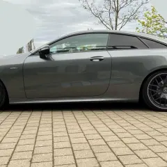 Szary Mercedes-AMG E53 coupe z przyciemnianymi szybami i czarnymi felgami stoi na kostce brukowej.