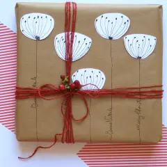 Confezioni pacchi regalo creativi con fiori stilizzati e bacche rosse, legati con spago rosso. Scritte "Buon Natale" e "Merry Christmas".