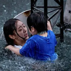 Dramatyczna scena z najlepszych filmów koreańskich: dziecko obejmuje tonącą kobietę w ulewnym deszczu.