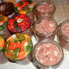 Słoiki z mielonym mięsem, gotowe do pasteryzacji. To pierwszy krok, jak zrobić kiełbasa w słoiku z galaretką.