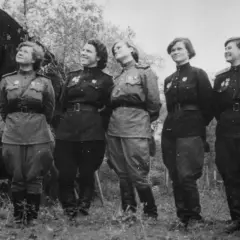 Seis mujeres con uniformes militares posan junto a un biplano. Son las brujas de la noche, listas para volar.