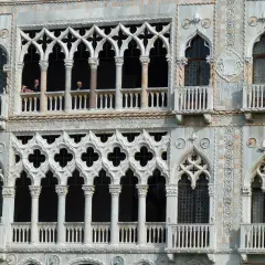 Dettaglio della Ca' d'Oro a Venezia, con le sue finestre traforate e balconi, dove si intravedono persone affacciate.