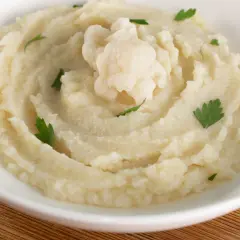 Aksamitne puree z kalafiora, udekorowane gałązką świeżej natki. Idealne jako lekki dodatek do obiadu.