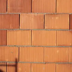Ściana z cegieł POROTHERM w zbliżeniu. Widoczne poziome spoiny zaprawy i pionowe kanaliki w cegłach.