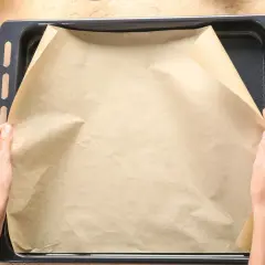 Ręce układają papier do pieczenia na blasze. Zastanawiasz się, czym zastąpić papier do pieczenia? Masz już składniki do ciasta.