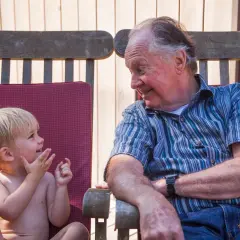 Un abuelo sonríe a su nieto, un momento tierno que los padres disfrutan al dejar a sus hijos con los abuelos.