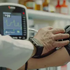 Lekarz mierzy ciśnienie pacjentowi. Na ekranie aparatu widoczny wynik ciśnienie 90/50.