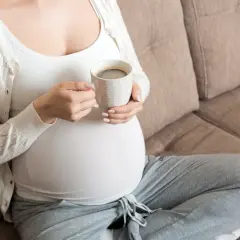 Ciężarna kobieta pije kawę, zastanawiając się, ile kofeiny w ciąży jest bezpieczne.