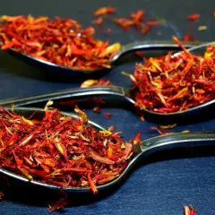 Trois cuillères remplies de filaments rouge orangé, une épice précieuse.