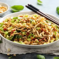 Pyszne danie z makaronem, mielonym mięsem i zielonymi warzywami, inspirowane przepisami na kapustę pak choi. Posypane orzeszkami ziemnymi.