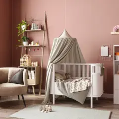 Une chambre de bébé chaleureuse avec un lit à baldaquin, une chaise confortable et des étagères pleines de jouets. Parfait pour une diy déco chambre bébé.