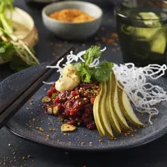 En konstnärlig koreansk råbiff med päron, koriander och krispiga nudlar. En utsökt rätt som väcker aptiten.