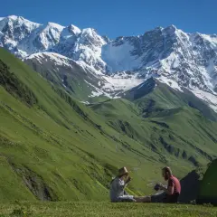Para odpoczywa przy namiocie na tle majestatycznych gór podczas wycieczki do Gruzji.
