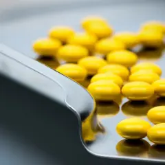 Żółte tabletki, być może tetracyklina, leżą na metalowej tacy.