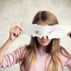 Dziewczynka z kartką zasłaniającą oczy, na której narysowano oczy. Czy to maska, czy objaw mitomanii?